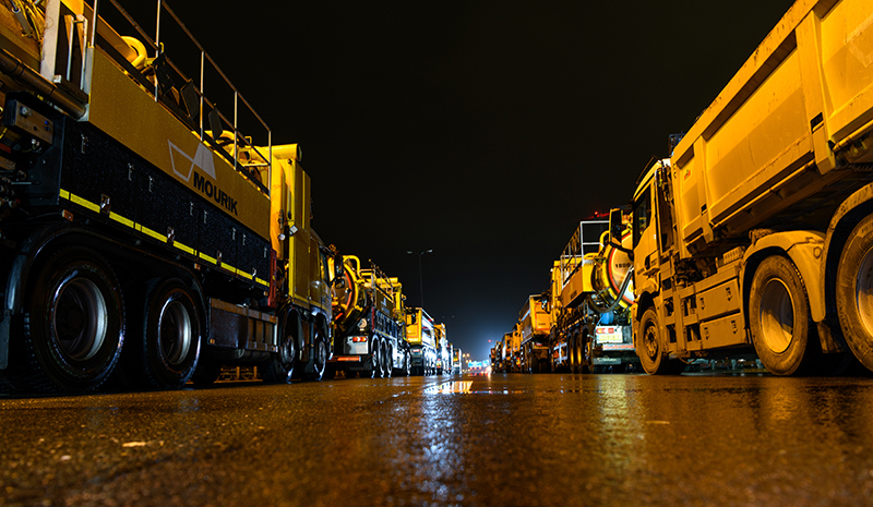 Vrachtwagens staan in het donker achter elkaar op een nat wegdek