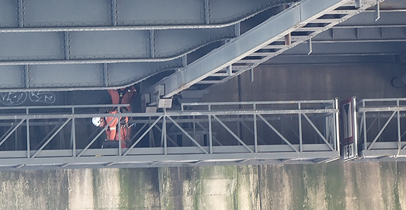 Twee medewerkers bezig met inspectie aan de onderzijde van de brug