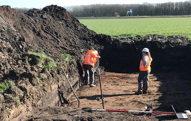 Twee medewerkers in een stuk uitgegraven grond